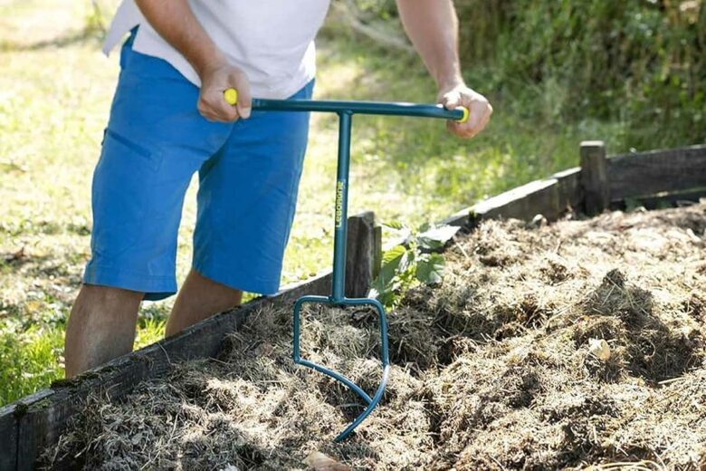 Un homme aère son compost avec l'outil Leborgne.