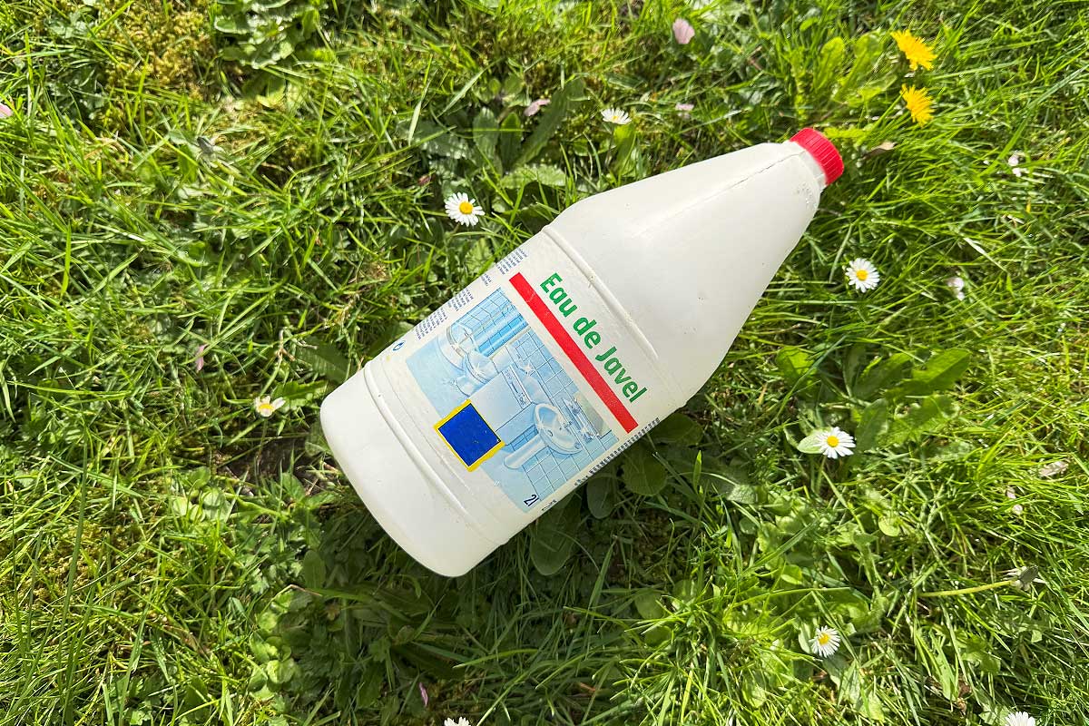 Un bidon d'eau de javel sur l'herbe.