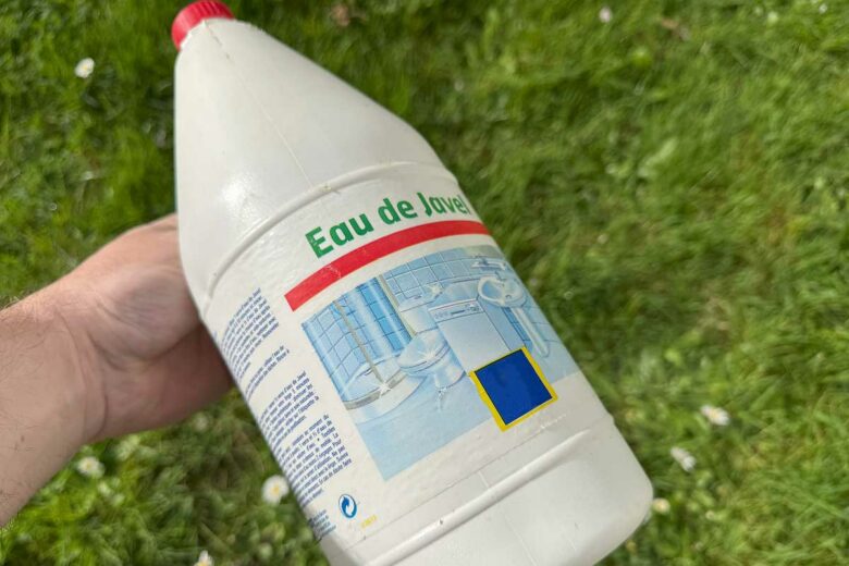 Une personne tient un bidon de javel.