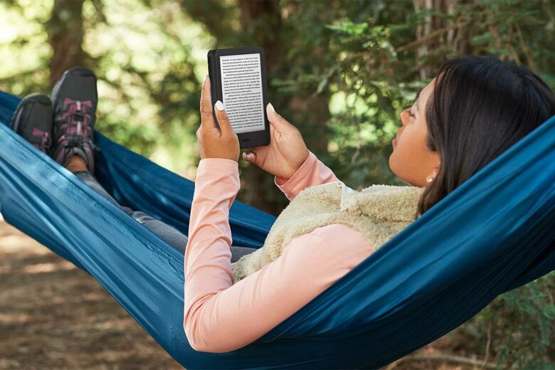 Une femme lit sur une liseuse dans un hamac.