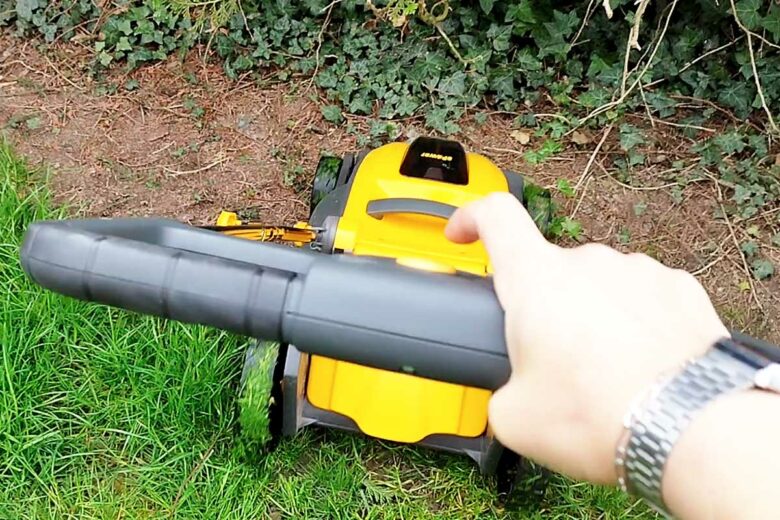 Une personne utilise une tondeuse pour entretenir son jardin.