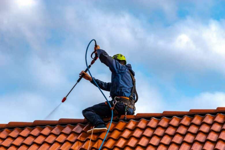 Un homme nettoie une toiture avec un Kärcher.
