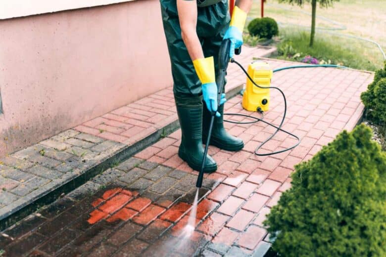 Un homme décolle la saleté avec un nettoyeur haute pression.