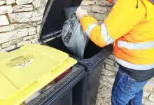 Un homme dépose un sac-poubelle dans son bac.