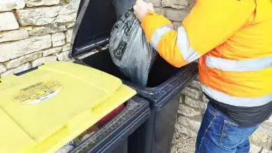 Un homme dépose un sac-poubelle dans son bac.