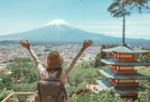 Une personne les bras levés devant un paysage japonais et le mont Fuji à l'horizon.