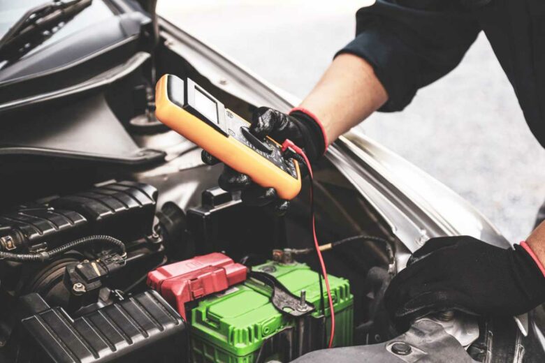Un garagiste vérifie la batterie d'une voiture thermique.