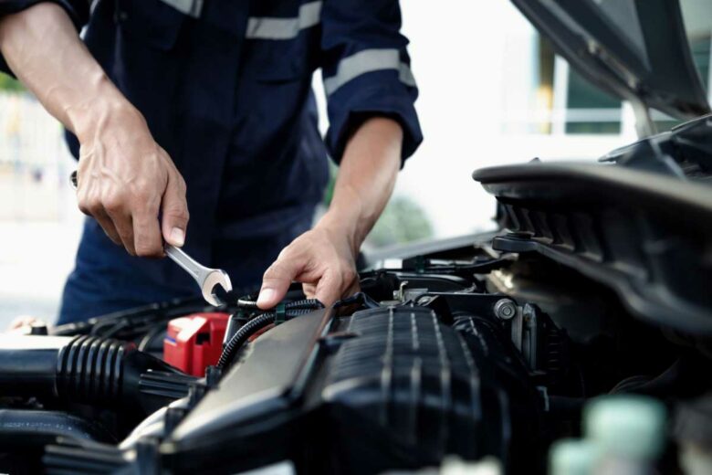 Un garagiste s'occupe du moteur d'une voiture.