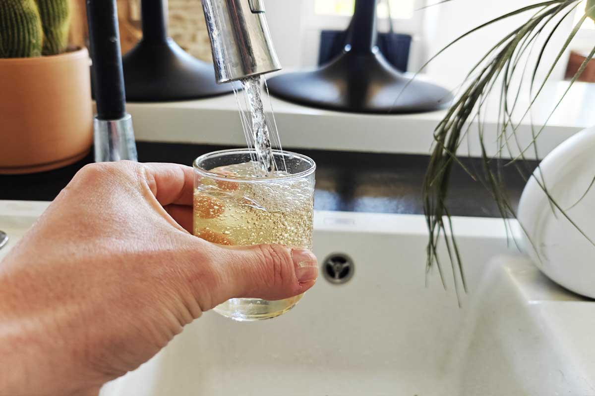 Une personne se verse un verre d'eau du robinet.