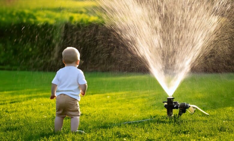 Un enfant devant un système d'arrosage automatique.