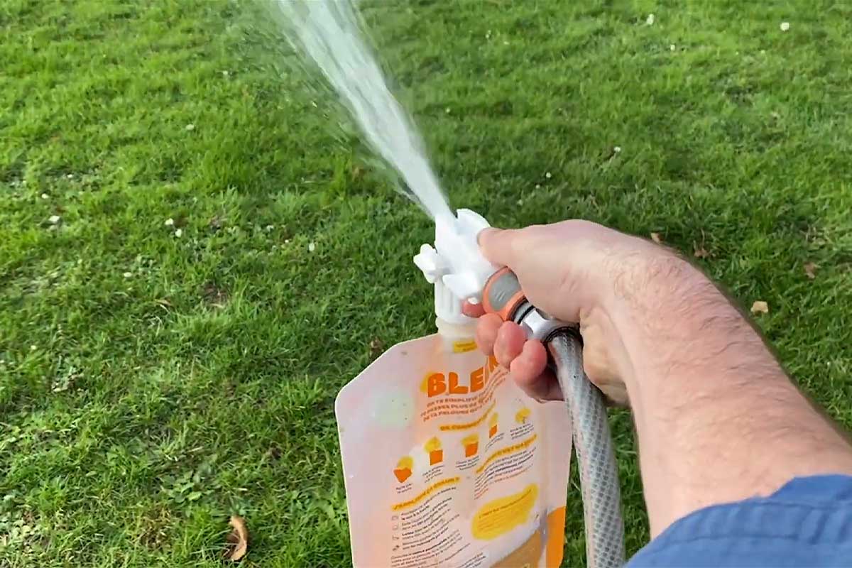 Une personne entretient sa pelouse avec un engrais Bleen.