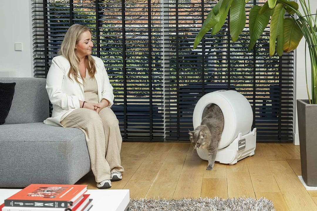 Une femme qui regarde son chat sortir de sa litière.