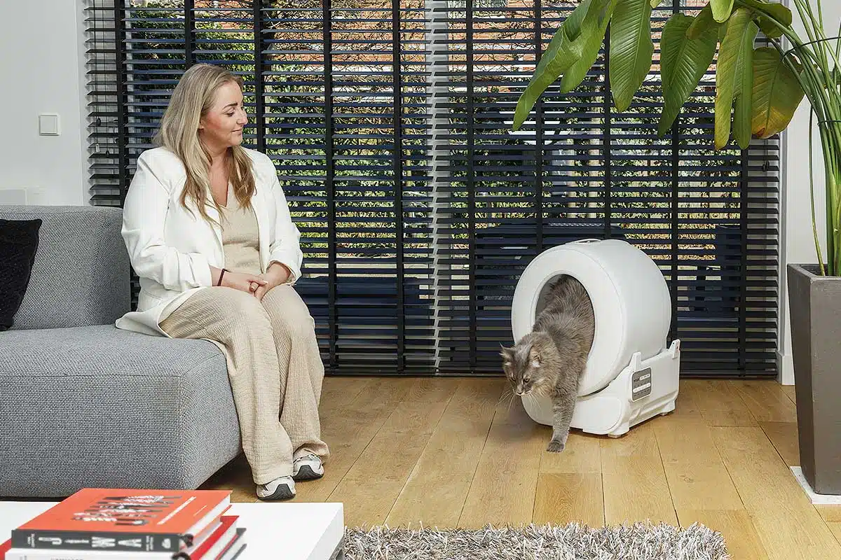 Une femme qui regarde son chat sortir de sa litière.