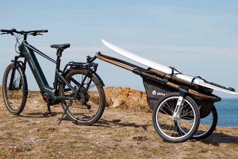 Un vélo électrique avec une remorque transportant une planche de surf.