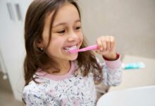 Une petite fille se brosse les dents.