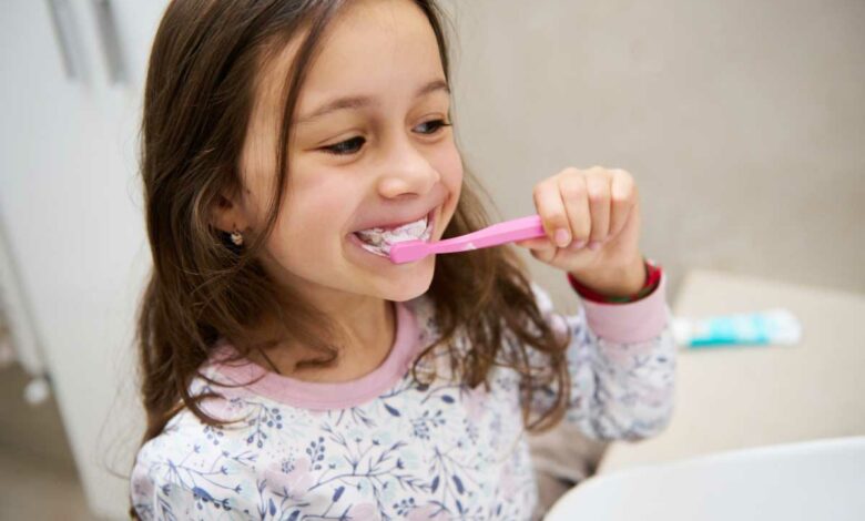 Une petite fille se brosse les dents.
