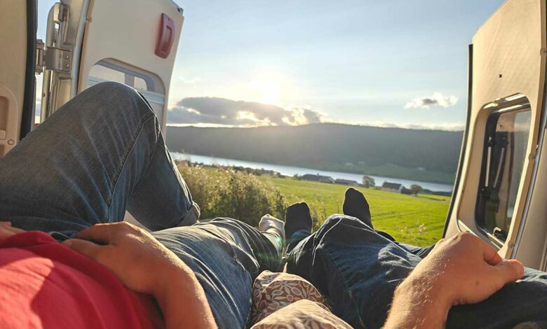 Des personnes contemplent le paysage dans leur van aménagé.