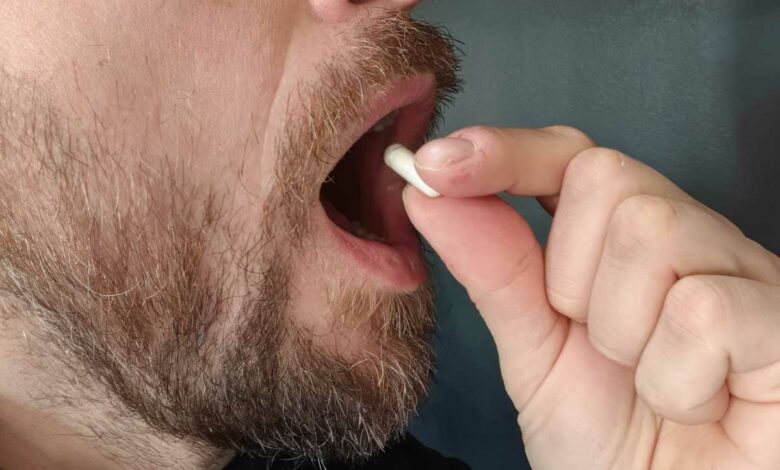 Un homme prend une gellule.