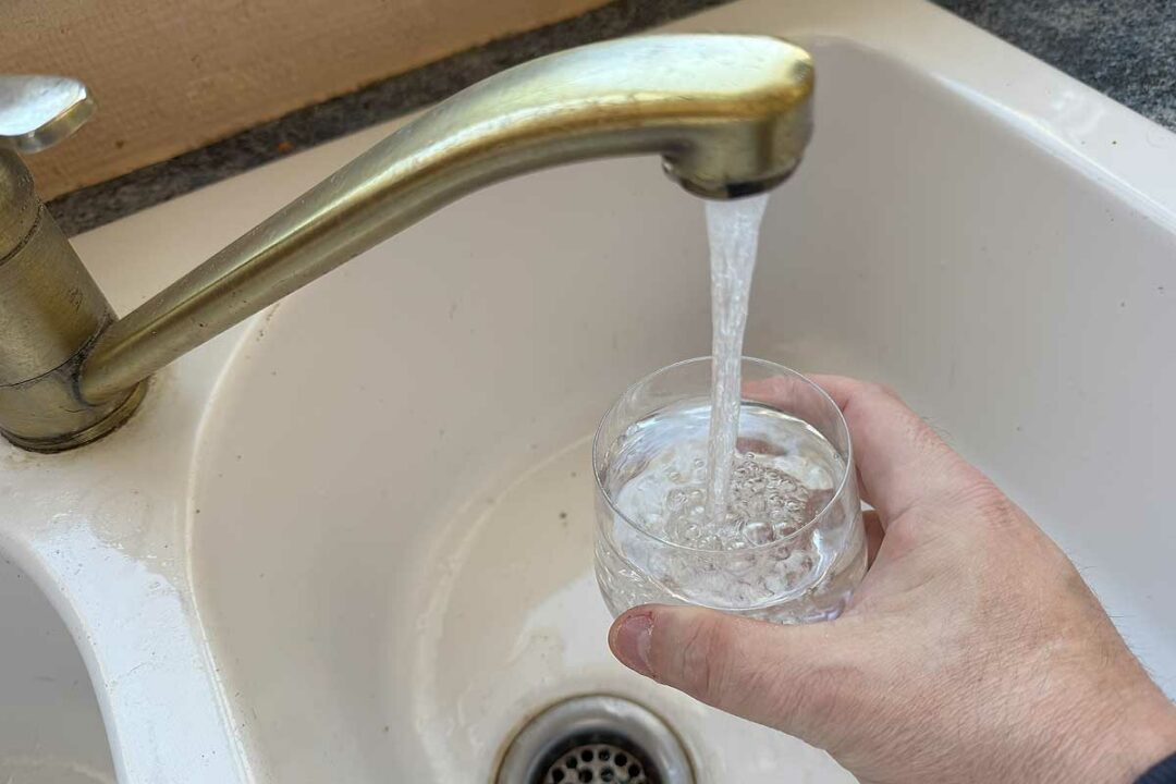 Une personne se verse un verre d'eau du robinet.