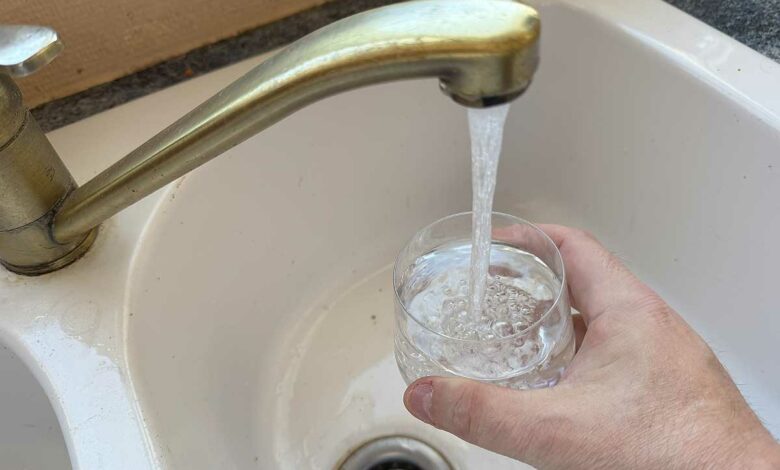 Une personne se verse un verre d'eau du robinet.