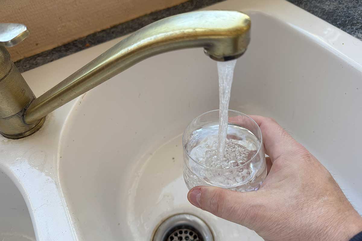 Une personne se verse un verre d'eau du robinet.