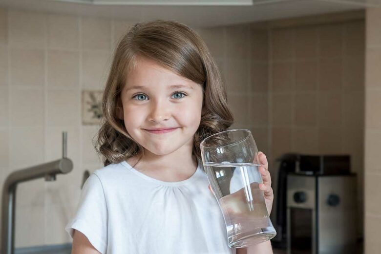 Une enfant boit un verre d'eau.