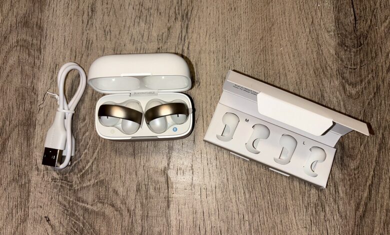 Les Soundcore AeroClip by Anker en rose cuivré et blanc, bien installés dans leur boîtier, prêts à être testés.