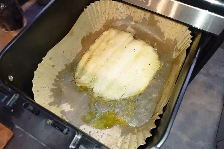 Un poisson cuit au airfryer dans un moule en papier cuisson.