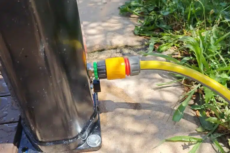 Une douche solaire branchée à un tuyau d'arrosage.