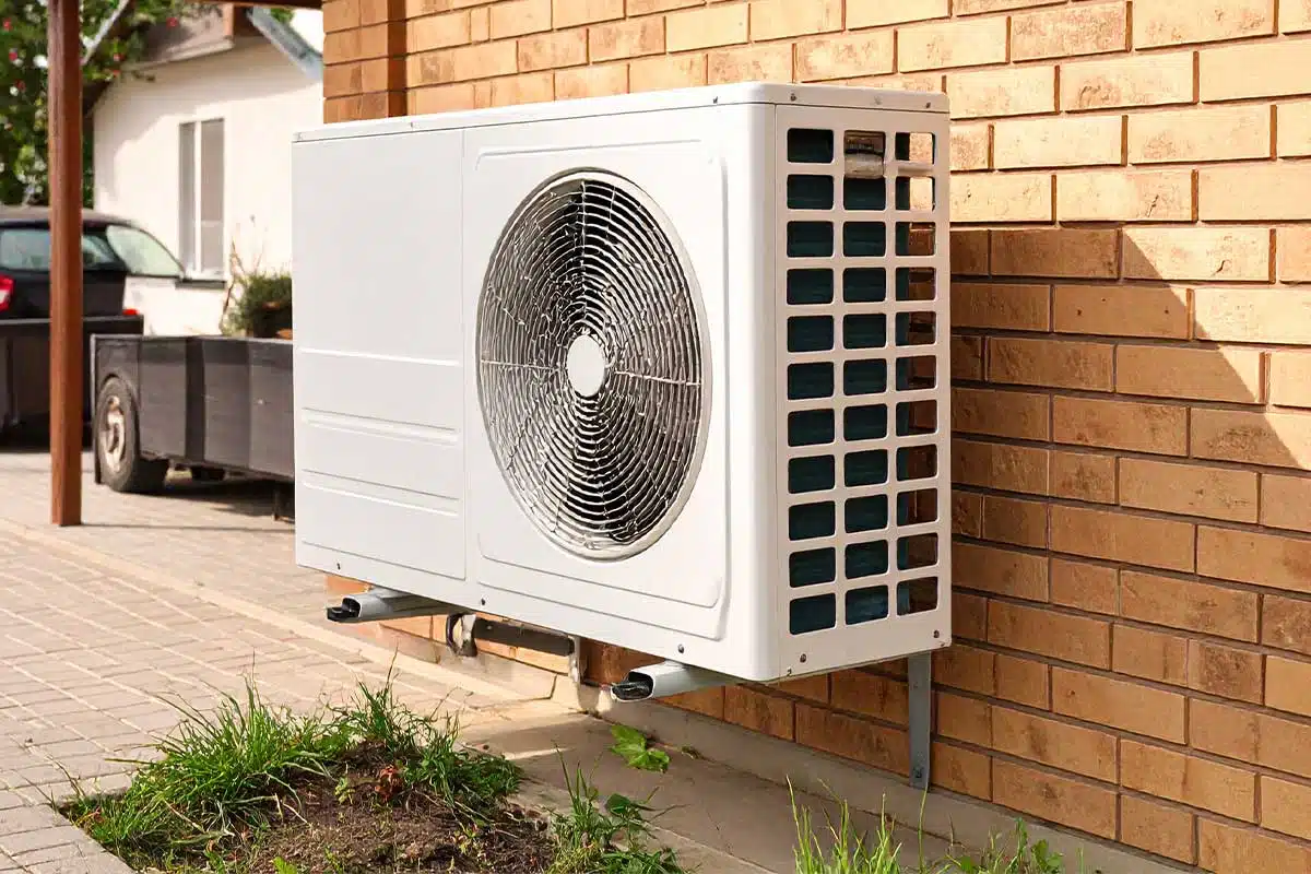 Une pompe à chaleur contre le mur du garage.