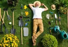 Un jardinier allongé dans le jardin au milieu d'outils.
