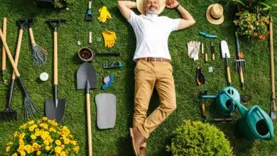 Un jardinier allongé dans le jardin au milieu d'outils.