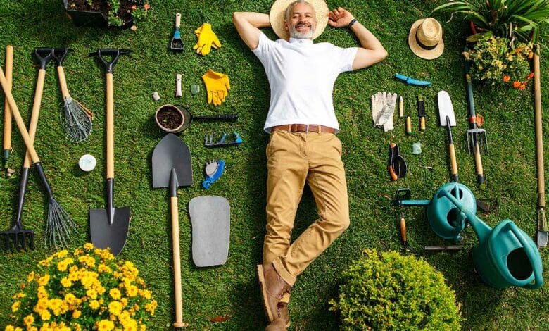 Un jardinier allongé dans le jardin au milieu d'outils.