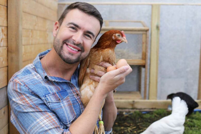 Un homme tient une poule et deux œufs dans ses bras.