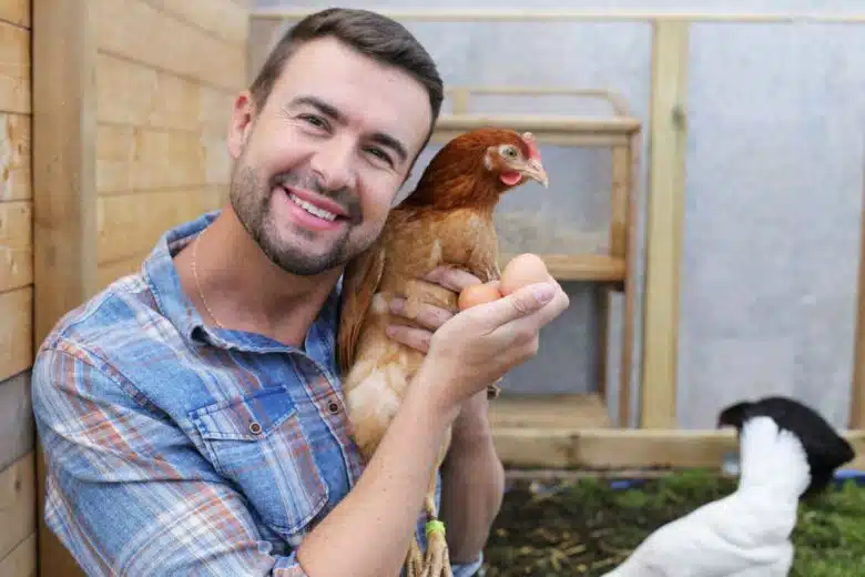 Un homme tient une poule et deux œufs dans ses bras.