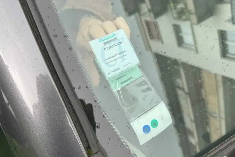 Une personne retire sa vignette verte de son pare-brise.