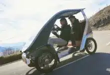 Un vélomobile sur la route avec deux personnes à bord.