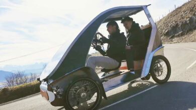 Un vélomobile sur la route avec deux personnes à bord.