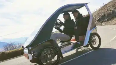 Un vélomobile sur la route avec deux personnes à bord.