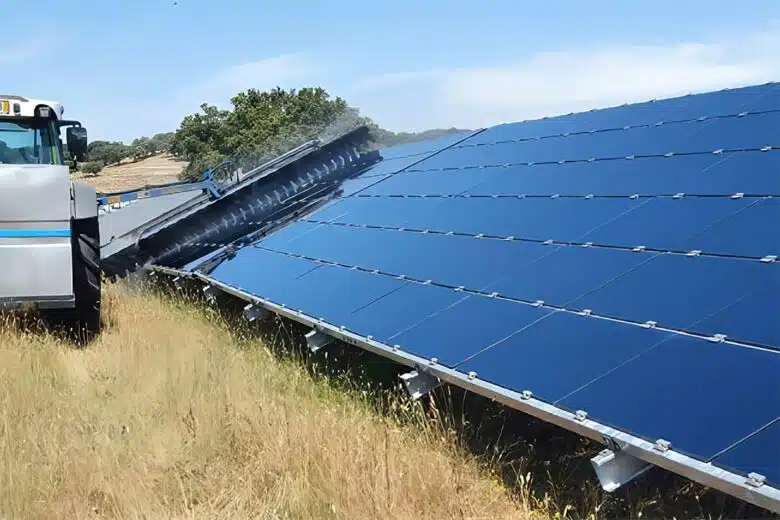 Un tracteur muni d'une brosse spéciale pour nettoyer les panneaux solaires.