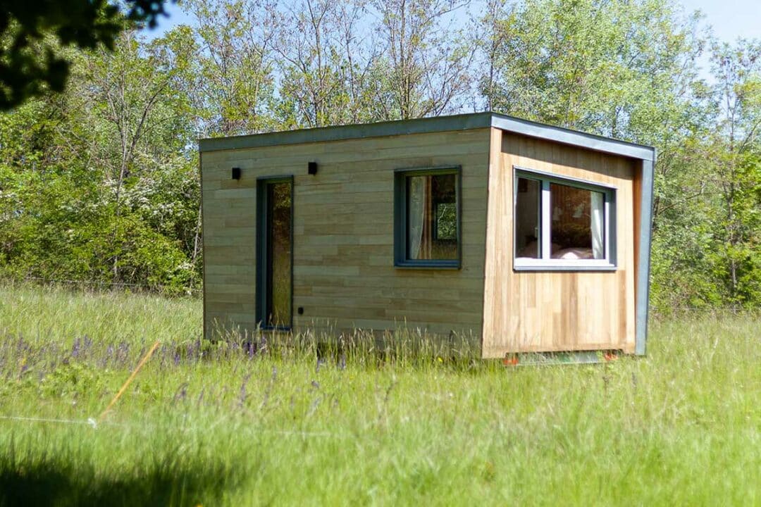 Une tiny house au milieu d'un pré.