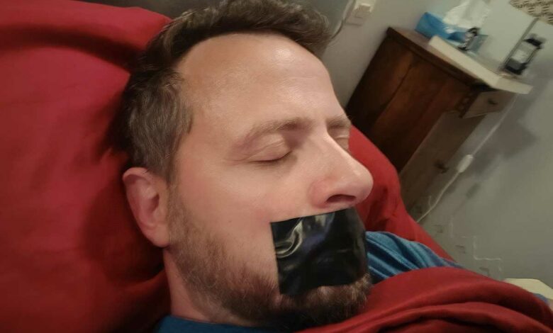 Un homme dort la bouche scotchée.