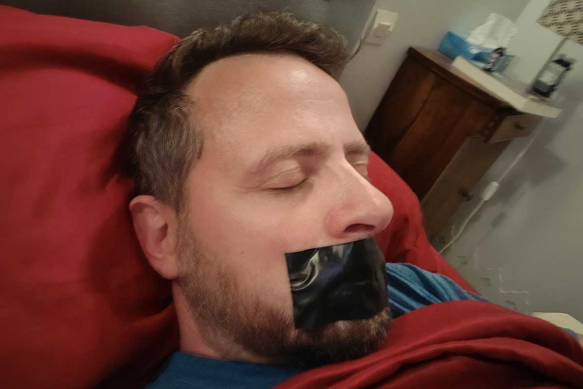 Un homme dort la bouche scotchée.