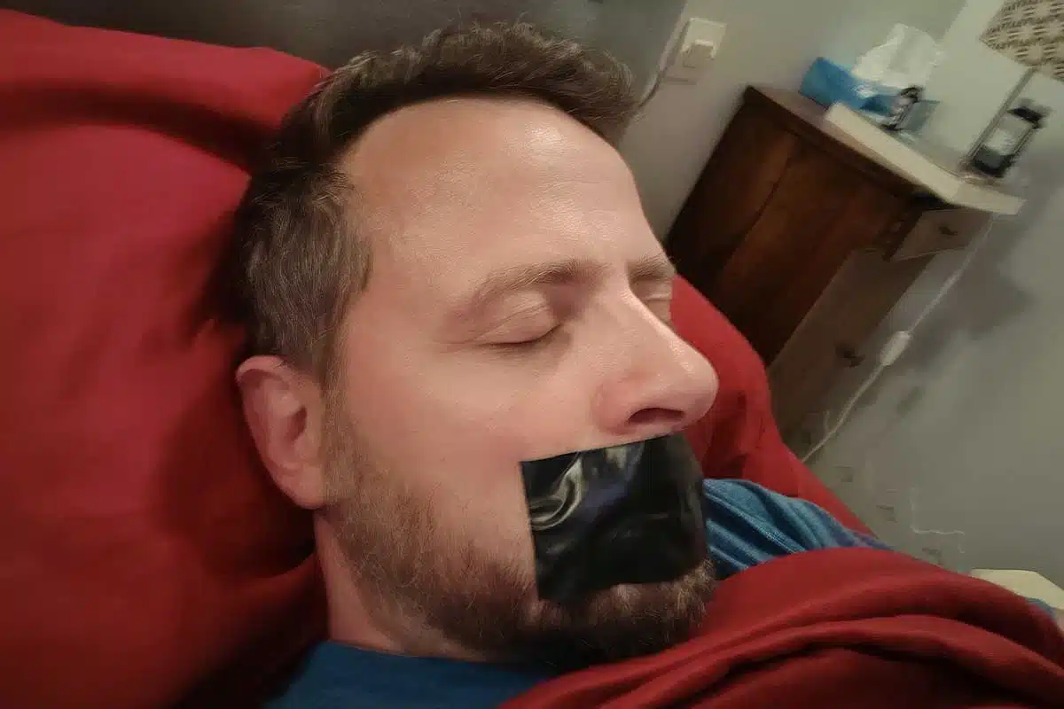 Un homme dort la bouche scotchée.