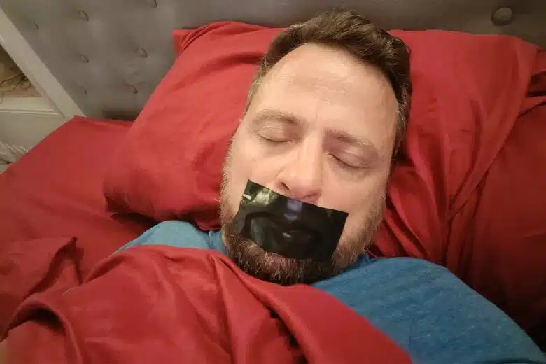 Un homme dort avec un scotch sur la bouche.