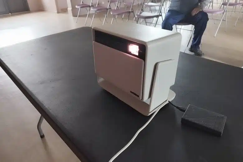Vidéoprojecteur XGIMI Horizon S Pro en pleine projection lors de l’installation dans la salle des fêtes, posé simplement sur une table noire.