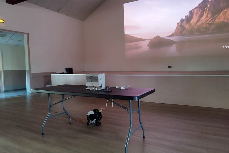 Mise en place du XGIMI Horizon S Pro dans la salle communale, avec une projection en cours sur un grand mur clair.