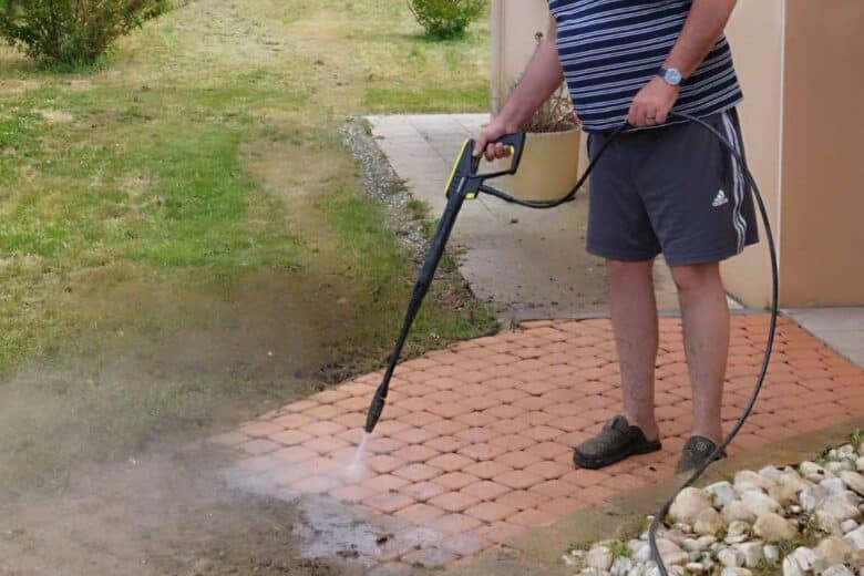 Un homme utilise un nettoyeur haute pression pour nettoyer une allée très sale.