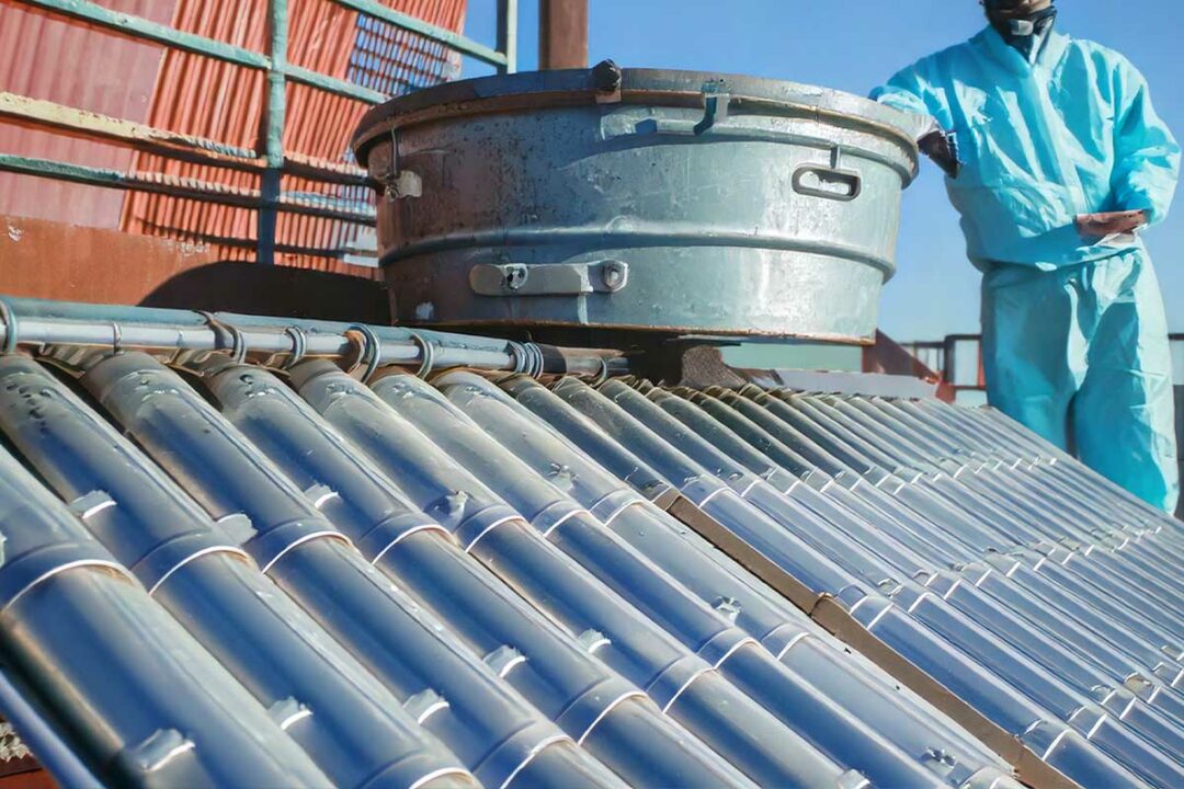 José Alano, mécanicien à la retraite devant son chauffe-eau solaire fait maison avec des bouteilles en plastique.
