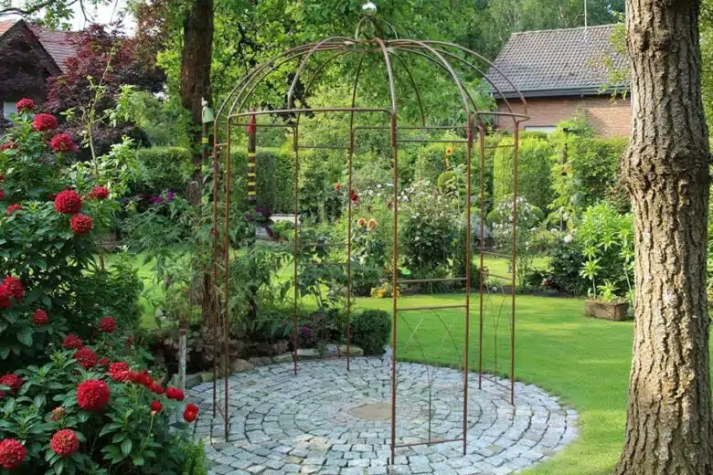 Une gloriette sur un sol pavé dans le jardin.